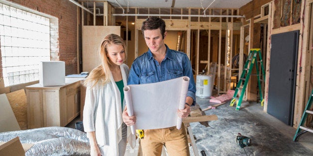 Caucasian couple reading blueprints at construction site