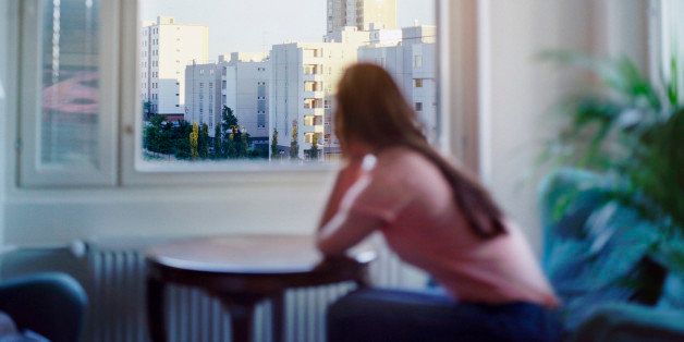 Woman looking through apartment window, Espoo, Finland