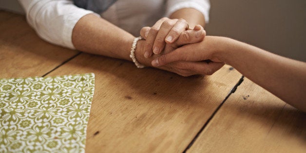 A cropped shot of a woman holding a loved one's hand in support