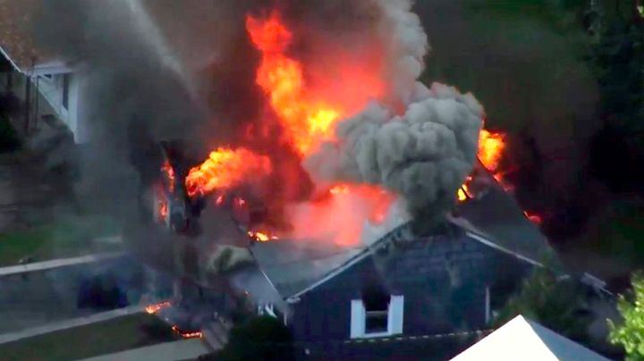 In this image take from video provided by WCVB in Boston, flames consume the roof of a home in Lawrence, Mass.