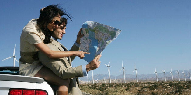 Affectionate young couple standing at roadside with map.