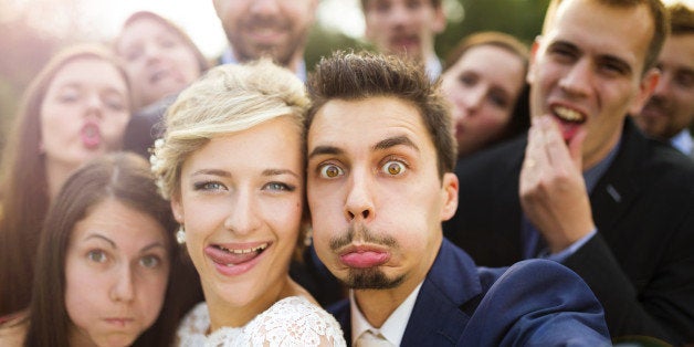 Young couple of newlyweds with group of their firends taking selfie and making funny grimaces