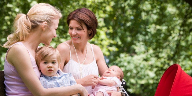 Mothers with holding children on park bench