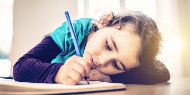 pensive cute little girl drawing at desk with color pen