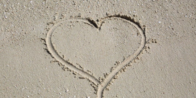 Heart-shape drawn in wet coral and shell sand, Komandoo, Maldives, Indian Ocean.