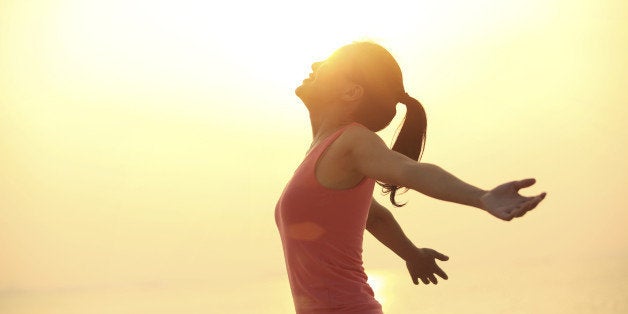 cheering woman open arms at sunrise beach