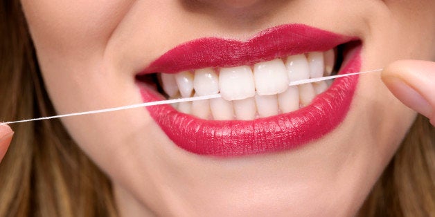 young woman teeth with dental floss.