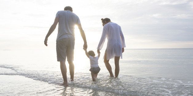 a young family walking in the sea at the beach in thailand
