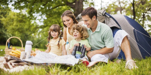 Young parents with their little children enjoying in family camping. 