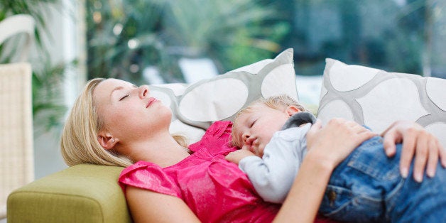 Woman napping on sofa with baby boy