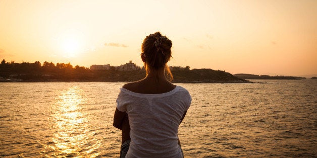 beautiful model girl sitting on the rock by the sea