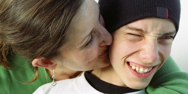 Mother kissing teenage boy (14-16) on cheek, close-up