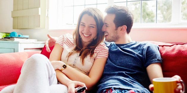 Young couple laugh together as they relax on sofa
