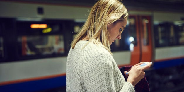 Woman with smart phone in train station