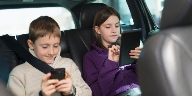 USA, New Jersey, Jersey City, Boy and girl (8-9, 10-11) using digital tablet and smart phone in car