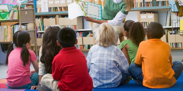 Kindergarten teacher reading to children in librar