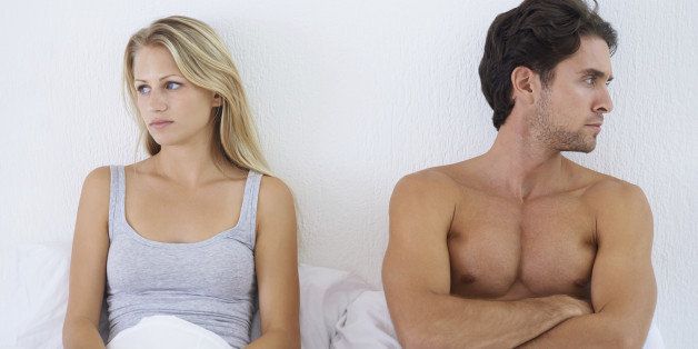 A couple sitting in bed and looking upset after having a disagreement