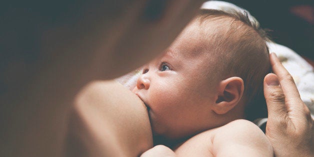 Mother holding and breast-feeding little baby