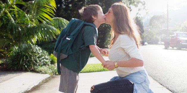 Boy kissing mother goodbye walking to school