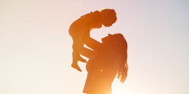 mother and little daughter play at sunset sky