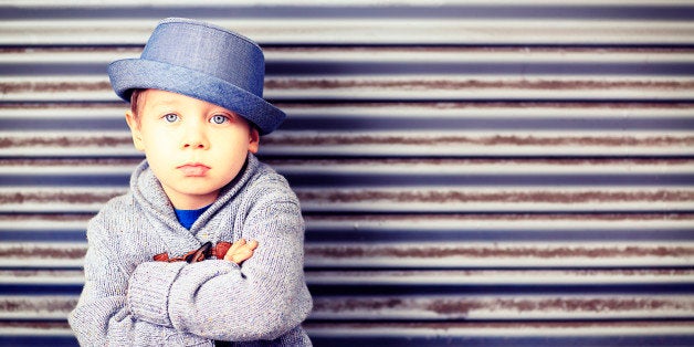 A cute, four year old little boy wearing a fedora style hat and sweater, sitting with his arms crossed. Kids fashion, back to school concept. Similar images.