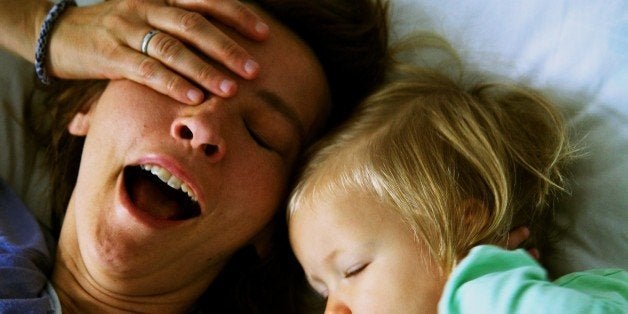 Tired mother yawning with her one year old baby.