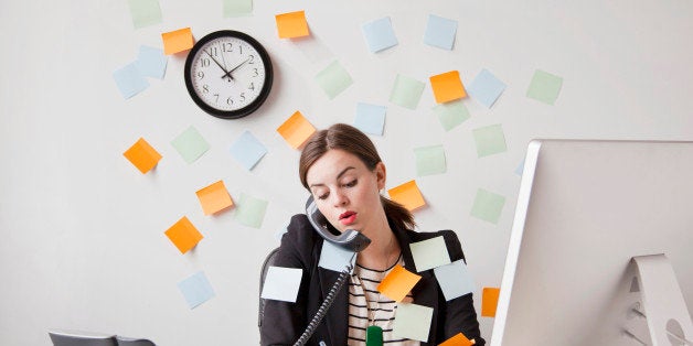 Studio shot of young woman working in office covered with adhesive notes