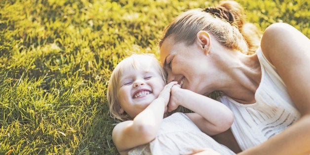 Happy mother and baby laying on meadow