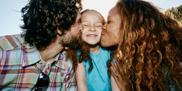 Parents kissing cheeks of daughter outdoors