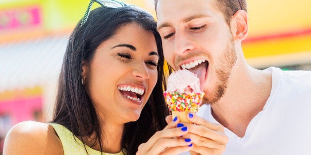 Hispanic couple sharing ice cream cone outdoors