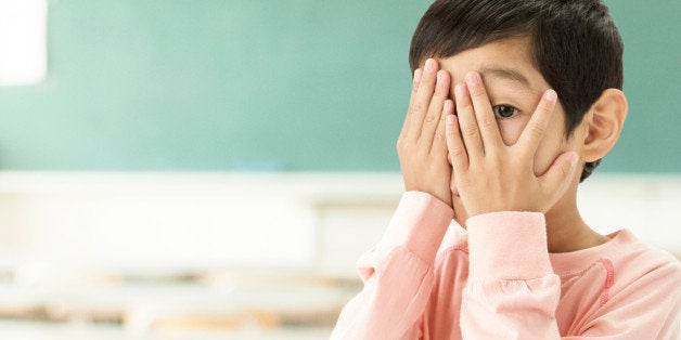 Portrait Of Scared Little Boy Looking Through Fingers