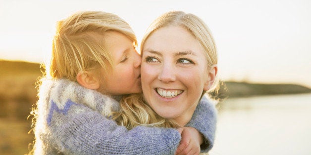 Loving son kissing mother on cheek while enjoying piggyback ride at lakeshore