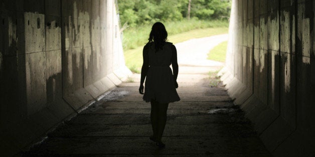 A young woman moving out of darkness into light.