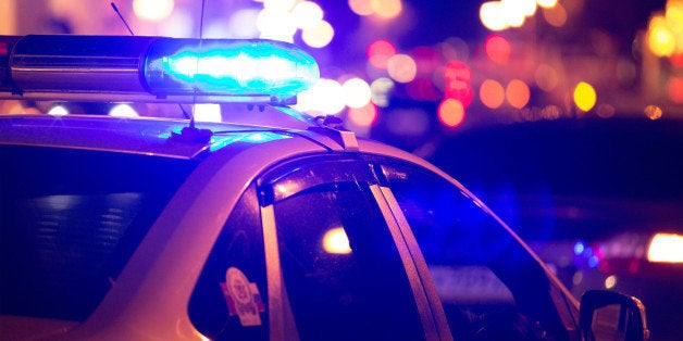 Blue light flasher atop of a police car. City lights on the background. 