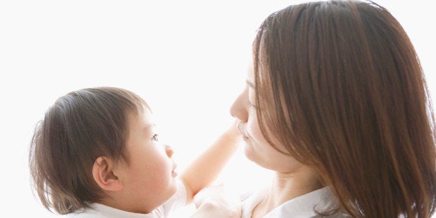 Mother holding baby boy in arms, side view