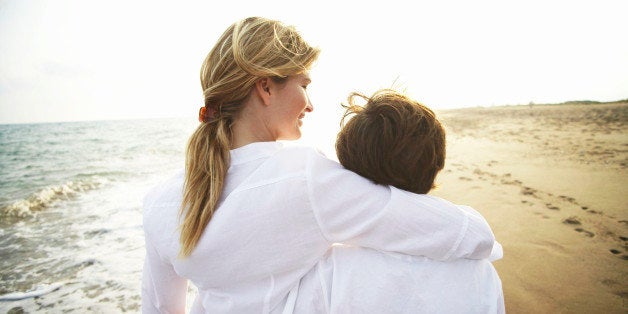 Mother and son (8-10) walking on beach, rear view, close-up