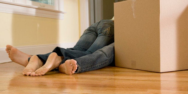 Woman laying on man behind moving boxes