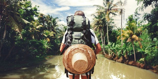 Traveler woman with backpack standing near big tropical river at sunny day