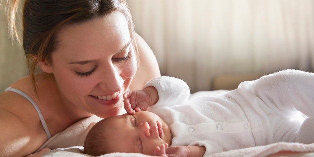 Mother admiring newborn baby on bed