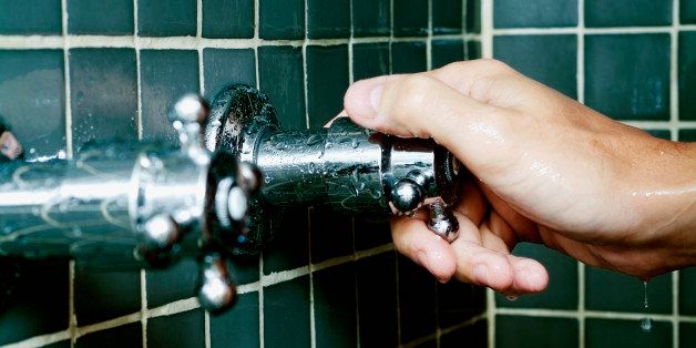 Close-up of a person's hand turning a shower knob