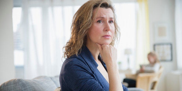 Concerned Caucasian woman sitting on sofa
