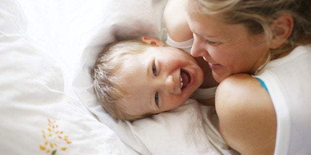 A 3 years old boy in his bed with his mom