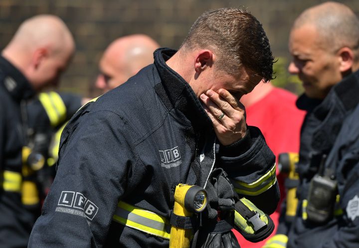 A firefighter looks at the floral tributes left by the Latymer Community Centre before a minute's silence near to Grenfell Tower in west London after a fire engulfed the 24-storey building on Wednesday morning.