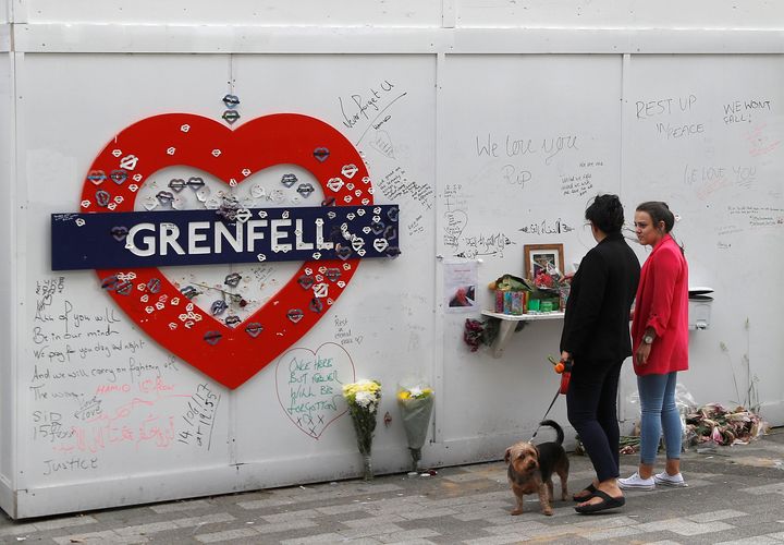 Women look at a hoarding covered in messages of condolence at the base of Grenfell tower one year after the fire in Britain, in London, June 13, 2018.