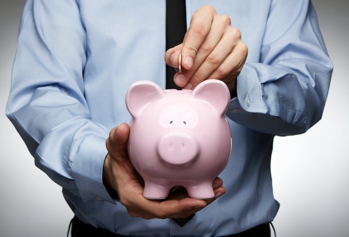 Male hand putting coin into a piggy bank