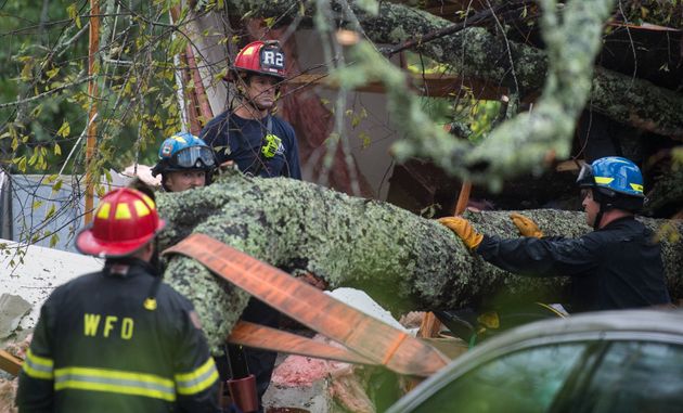 Firefighters work to remove a tree that fell on a house in North Caroline killing a mother and her child on Friday