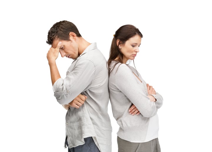 Young couple standing back to back having relationship difficulties on white background