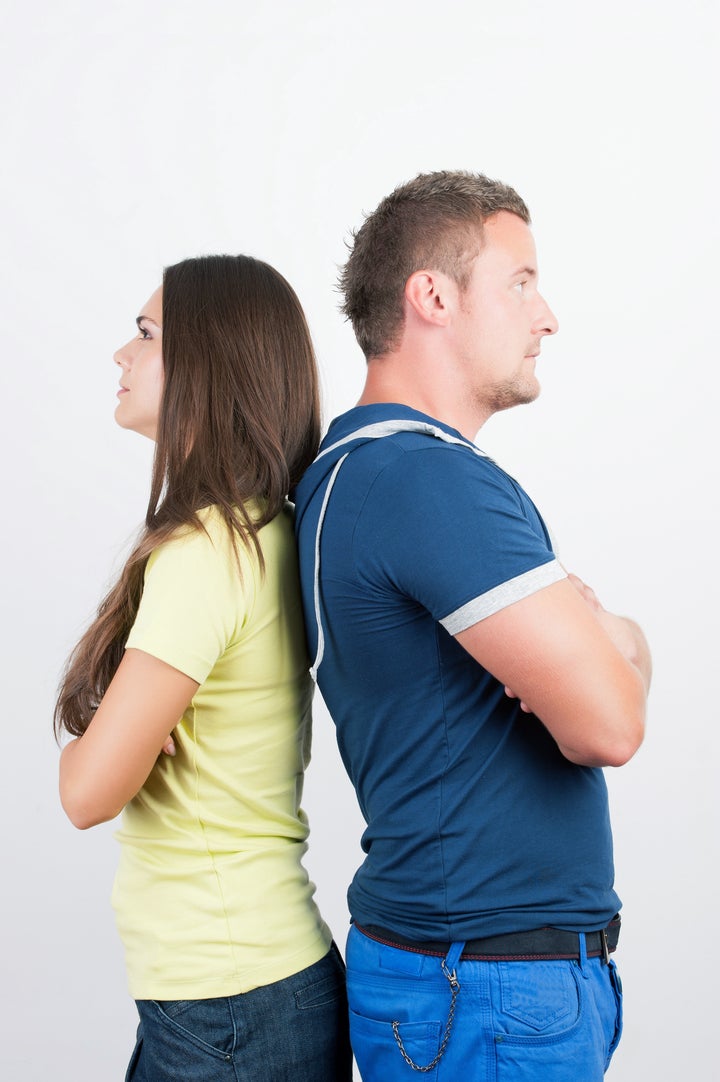 Young couple standing back to back having relationship difficulties on white background