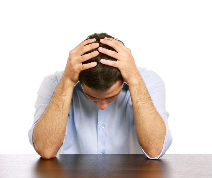 A man with a headache at the desk, isolated on white background