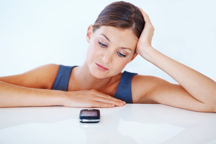 Portrait of upset business woman waiting for call over white background